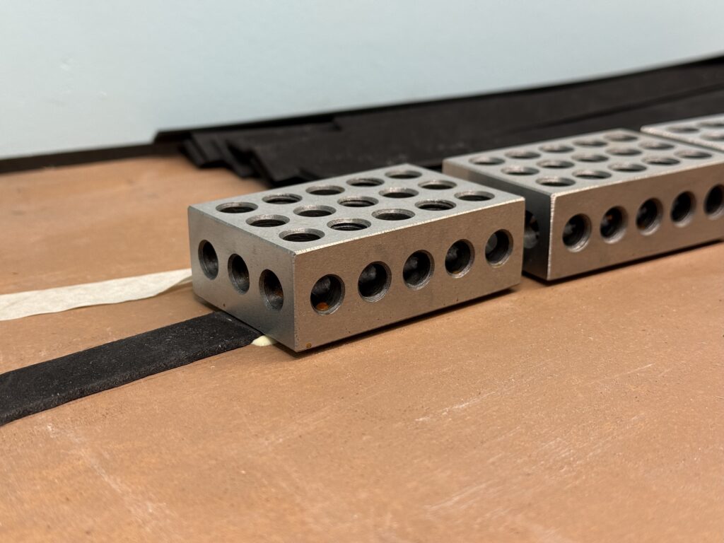 Holding the EVA foam down with metal blocks, while glue dries.