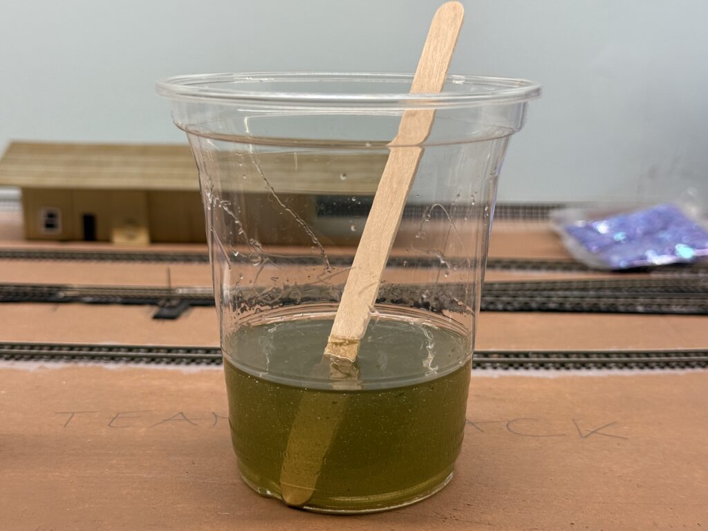 Adding drops of Vallejo Dark Olive Drab to the resin mix.